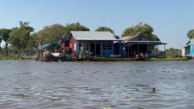 View from boat passing floating houses in Prek Toal village on Tonle Sap Lake Cambodia. Continuous scene of daily life on water in Southeast Asia.