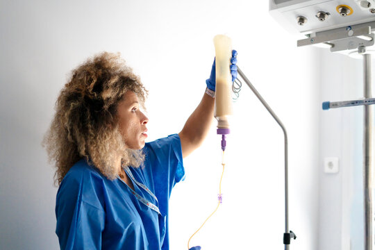Healthcare professional adjusting enteral feeding in hospital room