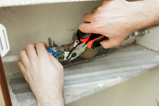 Close-up of a worker using pliers to attach a security seal to a water meter for utility fraud prevention. Stock photo