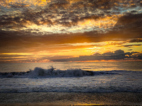 beautiful sunset on the beach with waves and clouds in the sky