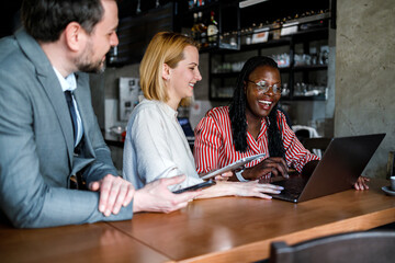 Fototapeta premium People work together in a cafe in the city during the day with laptops and smiles