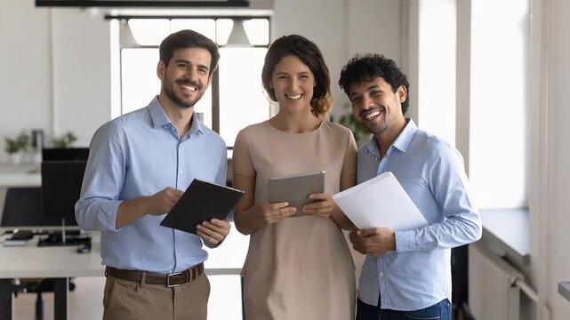 Three business colleagues discussing documents together in office environment showing collaborative professional workflow