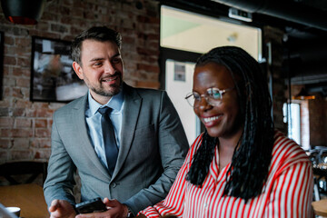 Fototapeta premium Two people talking and smiling in a cafe during lunch hours in a city