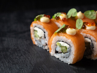 Japanese cuisine. Eating sushi roll with chopsticks  on a black platter © photopixel