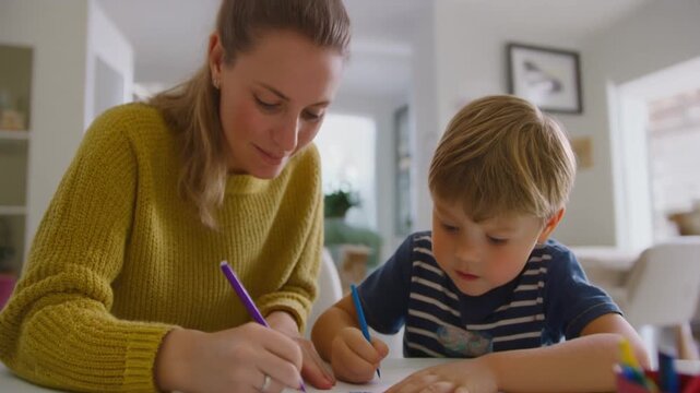 Mother and young child drawing together at desk in bright home interior showing supportive family learning lifestyle