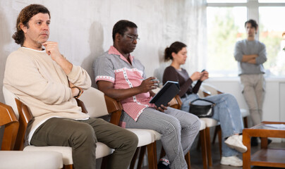 Fototapeta premium Group of people are waiting for their turn for an interview at the reception area in the office. Job seekers preparing for an interview with a recruitment manager at a marketing company