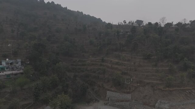 Aerial landscape view of Dwara village near Dehradun, Uttarakhand, showing misty mountains with terrace farming slopes and forests of sal, chir pine, khair, and sissoo on a winter evening.