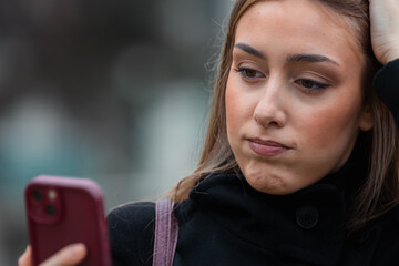 young woman looking at her mobile phone, looking worried