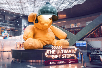Fototapeta premium 2 December 2025, Doha, Qatar: Lamp Bear artwork and a Formula 1 car are on exhibit at Hamad International Airport