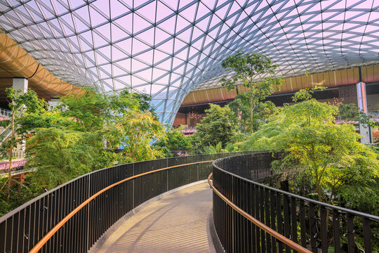 2 December 2025, Doha, Qatar: Walking bridge through indoor garden valley and modern architecture at Hamad Airport