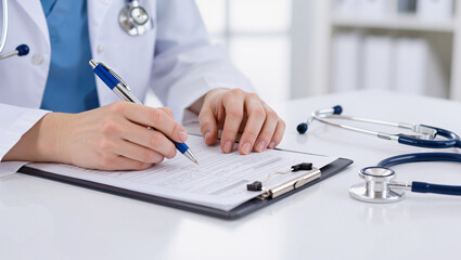 Fototapeta premium Doctor's Hand Filling Medical Record with Pen and Stethoscope on Desk