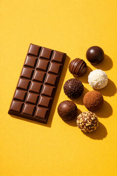 Barra de chocolate e trufas variadas em fundo amarelo vibrante