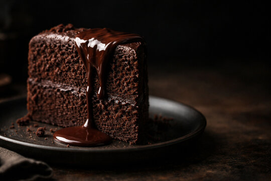 Fatia de bolo de chocolate com calda cremosa escorrendo em prato escuro