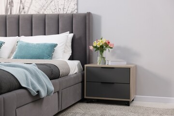 Comfortable bed with fresh linens and nightstand in room