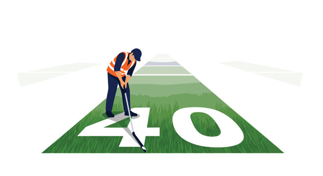 A worker in a safety vest and cap uses a line marker to paint the 40 yard line on a green football field.