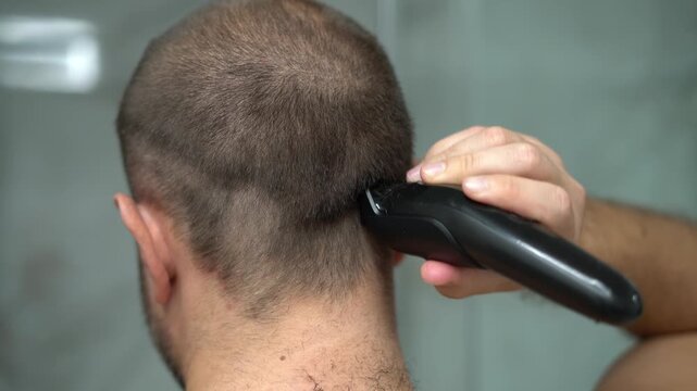 Man shaving head with electric clipper close up haircut