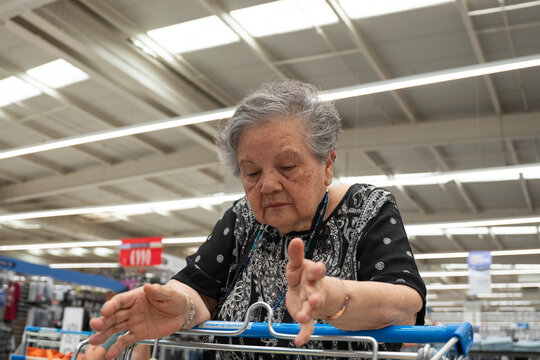 Mujer de tercera edad mirando su carro de compras en supermercado
