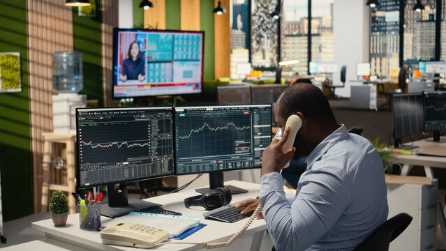 Stockbroker shocked by news of Black Swan event shaking global finance, calling customers to withdraw money. Scared African american man sees portfolio value drop from bear market crisis