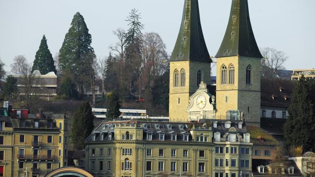 Panning shot across the historic architecture of the old town leading to the twin towers of the Church of St. Leodegar (Hofkirche) on a misty morning.