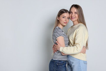 Naklejka premium Mother and her teenage daughter on light grey background, space for text