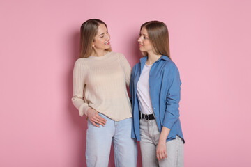 Fototapeta premium Mother and her teenage daughter on pink background