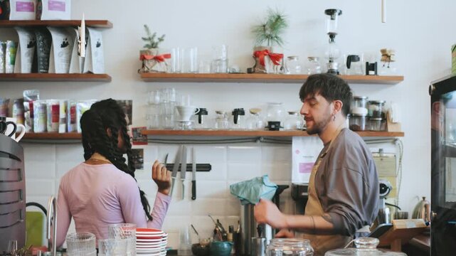 Barista and african american colleague dancing in a cafe while a customer enjoys their time at the counter in the morning