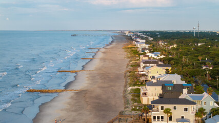 Naklejka premium Aerial view of shoreline and landscape of Folly Beach town near Charleston, South Carolina showcasing the coast, pier, and beach homes during morning sunrise