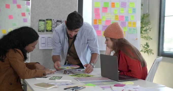 Diverse group of startup team engaging in brainstorming session, using sticky notes on glass wall to organize ideas, plan next steps. Creativity and collaborative spirit of modern entrepreneurial team