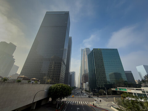 LOS ANGELES, CA, DEC 13, 2025: Downtown skyline with TCW and SMBC Manubank towers flanking a near-empty boulevard under dramatic smoky blue sky