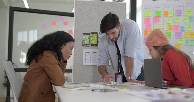 Diverse group of startup team engaging in brainstorming session, using sticky notes on glass wall to organize ideas, plan next steps. Creativity and collaborative spirit of modern entrepreneurial team