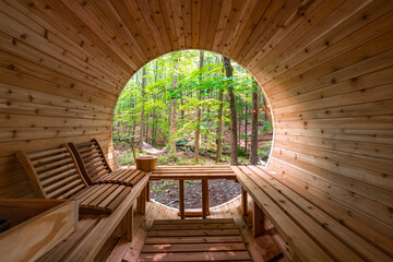 Wooden barrel sauna interior with forest view, bench seating and wellness retreat setting © nagelsphoto