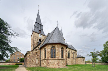 Fototapeta premium Historic St. Gereon church in Duerscheven, Germany. Impressive late Gothic architecture featuring a prominent choir and slate roof under cloudy skies.