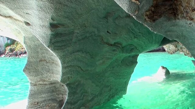 Experience the surreal beauty of Patagonia's Marble Caves. Aqua waters gently caress unique, sculpted marble formations, dazzling with sunlit reflections in this natural sanctuary.