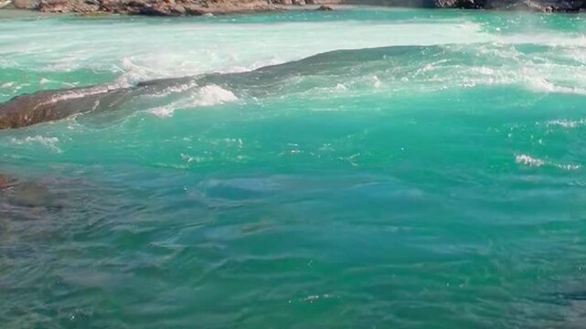 Vivid turquoise water swirls and rushes over rocks and small rapids in Los Alerces National Park, Argentina. The Patagonian landscape is truly breathtaking.