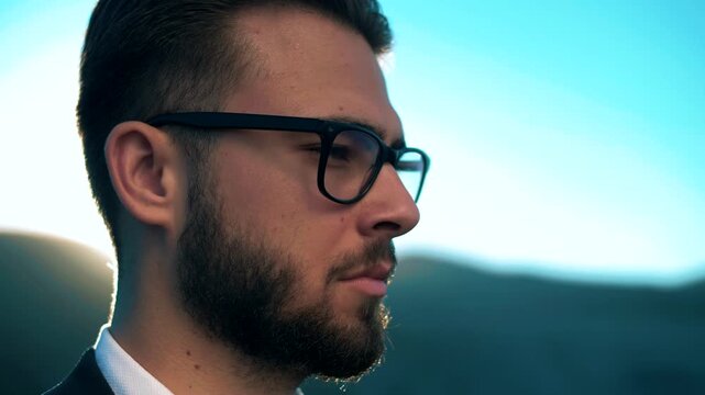 Successful male entrepreneur with glasses squinting and looking at the horizon. Close-up