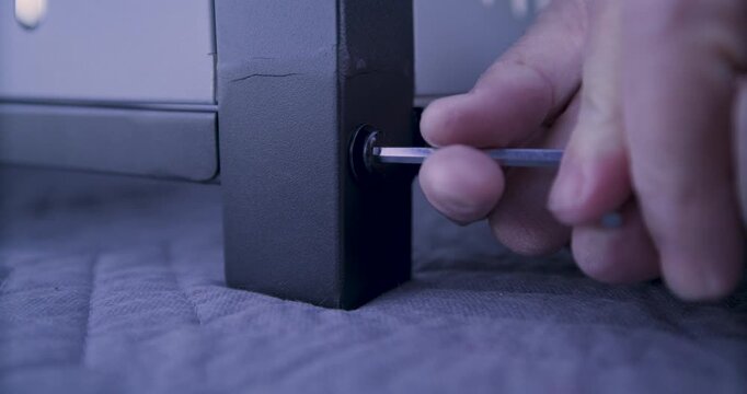 Low, closeup on man's hand screwing screw into bottom of cart leg