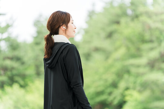 Women running, walking, jogging, or exercising in a park while wearing earphones (diet/sports)