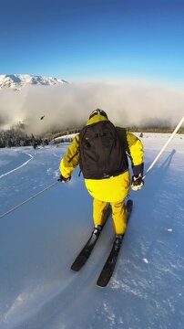 Thrilling Heliskiing Adventure: Freeride Skier Descends Majestic Snow-Covered Mountains on a Sunny Winter Day