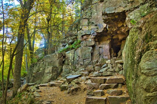 Autumn landscape featuring stone steps and a cave along a hiking trail in a colorful forest at Devil&rsquo;s Lake State Park near Baraboo, Wisconsin.