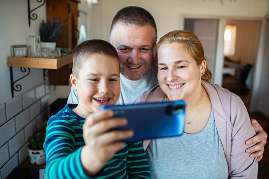 Parents and son taking selfie in home kitchen