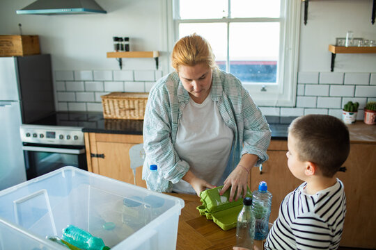 Woman and child sorting recycling in home kitchen