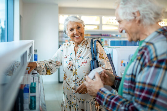 Smiling senior couple shopping for medicine at pharmacy