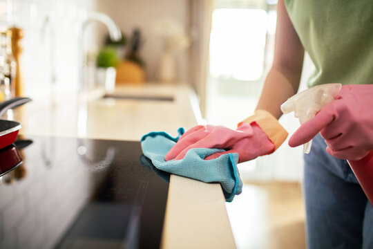 Person cleaning kitchen countertop with spray bottle at home