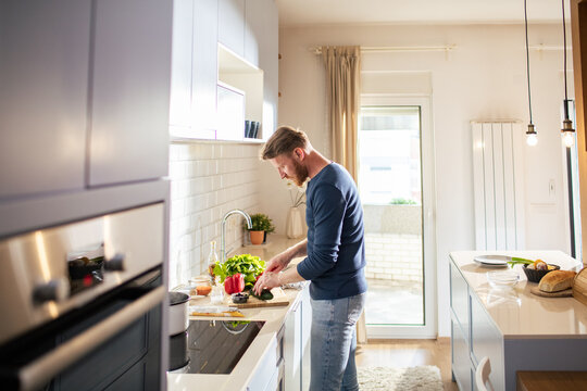 Young man chopping vegetables in modern home kitchen