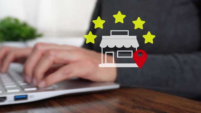 Close-up of a woman's hand working on a computer, pointing to an animated five-star rating for a local store.