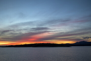 Sunset over lake and mountain silhouettes © MiguelA