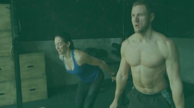 Partners holding squat, male leading arm swing causing explosive jumps for power, gym plyo box