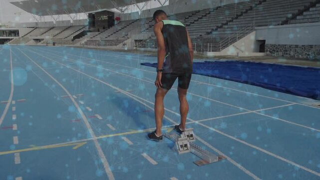 Male athlete walking to blocks, settling feet, placing hands, preparing sprint on blue track