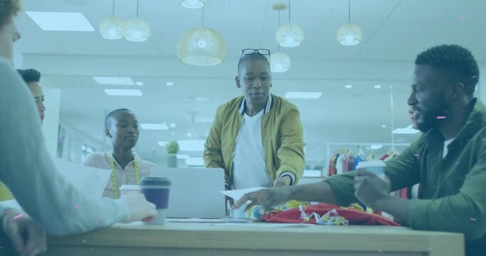 Vertical video: Design lead reaching for papers and handing sketches, guiding fashion team review