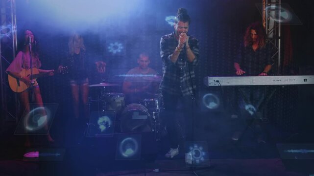 Band performing on live stage, lead singer holding microphone and bandmates playing instruments